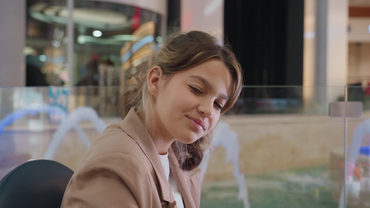 Reflejos de neón que resaltan un ambiente de ocio, escena de centro comercial con una mujer disfrutando de su tiempo libre entre luces de neón; clienta relajada girándose hacia la cámara en una fuente de centro comercial con reflejos de neón.