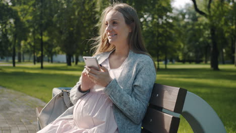 pregnant woman using mobile phone in a park