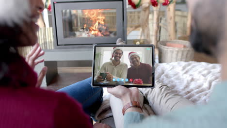 happy diverse couple, father and adult son having christmas tablet video call, slow motion