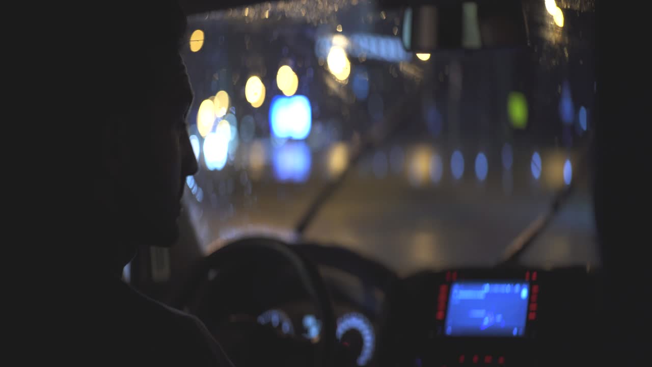 el joven conduce el automóvil en el camino lluvioso de la noche