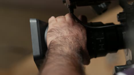 primer plano de una mano moviendo y enfocando la lente de una cámara de vídeo de estudio