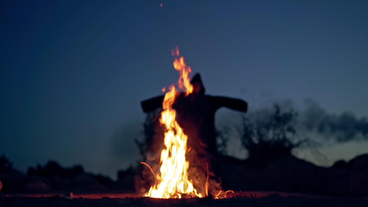 Horrible atmosphere at night outside. Bright flame with orange sparkles and dark nightmare with outstretched arms. Fright concept.