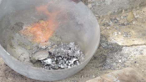 molten lead in a crucible with visible flames and fumes, in an industrial setting, top down view