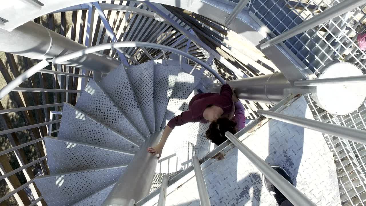 dos chicas bajan las escaleras desde la parte superior de la escalera de espiral sinuosa en la cubierta del punto de observación