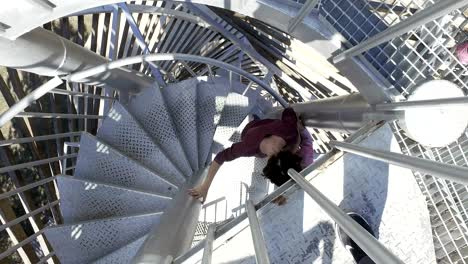 two girls go downstairs from top of winding spiral staircase on obserbation point deck