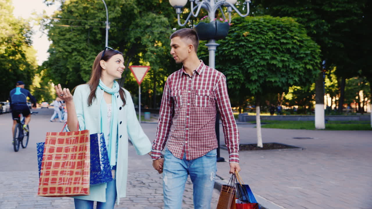 pareja joven caminando por la ciudad con bolsas de compras son felices sonriendo hablando