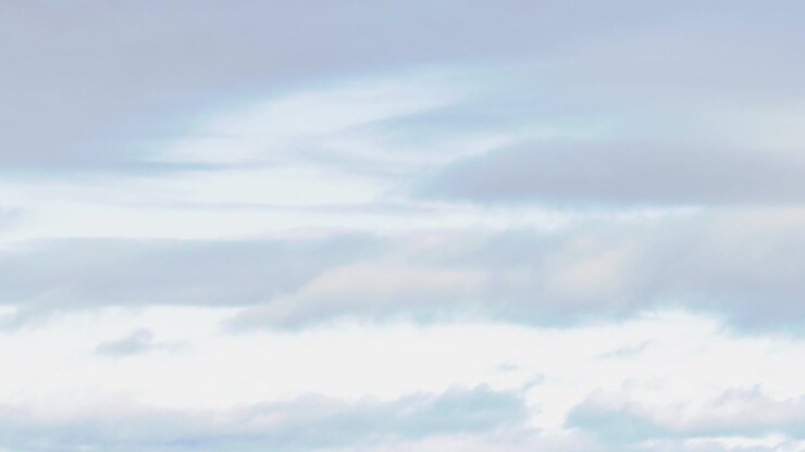 Wispy white and grey clouds move slowly across a bright, overcast sky with soft lighting.