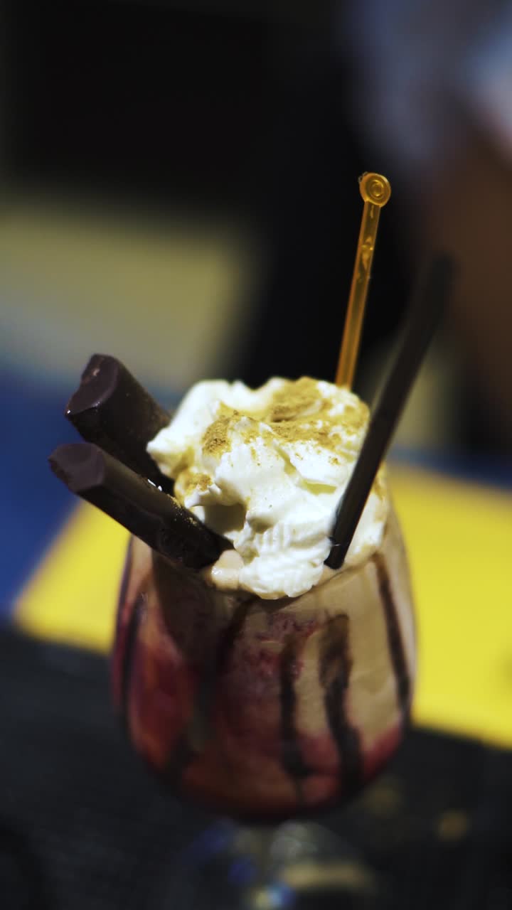 tomada vertical en primer plano de una bebida dulce elaborada en el bar del hotel, con chocolate, crema batida y relleno de cereza debajo