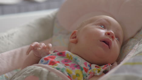 baby girl of two months lying in bouncy seat and yawning