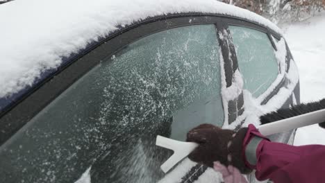 a hand removing ice from the car's surface - close up