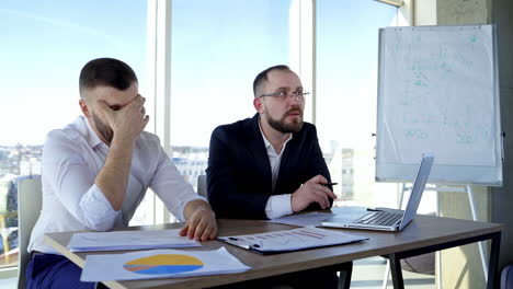 Businessmen brainstorm new ideas. Thoughtful partners sitting at the table and discus about the plan of their company in office. Portraits of two entrepreneurs.