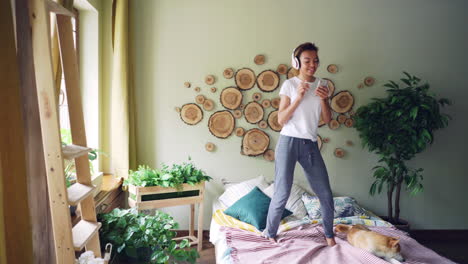 woman dancing on bed with headphones and phone