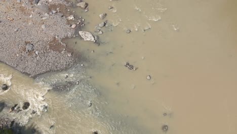 A-man-carries-river-stones-using-a-floating-tub-and-passes-through-the-river-flow