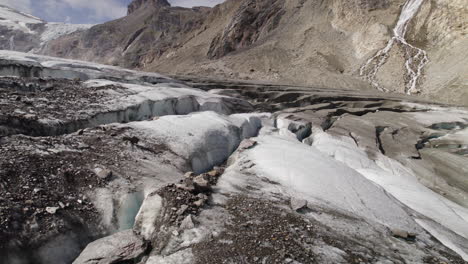 aerial closeup of pasterze glacier cracked surface partly covered by debris at the foot of the grossglockner mountain in high tauern national park, austria