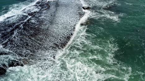 Hermoso-Ojo-De-Pájaro-En-La-Parte-Superior-De-Un-Dron-Aéreo-De-Olas-Aplastando-Una-Roca-Negra-En-La-Playa-De-Sibauma-Creando-Una-Piscina-Natural-Durante-La-Marea-Baja-Cerca-De-Pipa-En-El-Norte-De-Brasil