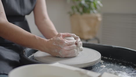 a female potter's wheel sculpting teacher explains how to work and teaches an elderly woman to work with clay and make mugs and jugs. master class for pensioners. pottery courses