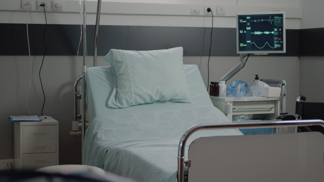 Empty bed in hospital ward with medical equipment