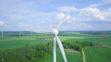 aerial view of wind turbines generating renewable energy in the wind farm, sunny summer day, lush green agricultural cereal fields, countryside roads, wide angle drone shot moving forward