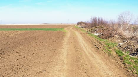 Garbage-by-the-country-dirt-road,-aerial-shot