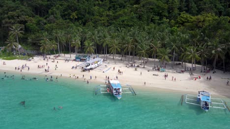 aerial : seven commandos beach packed with island hopping tourists and filipino banca outrigger boats