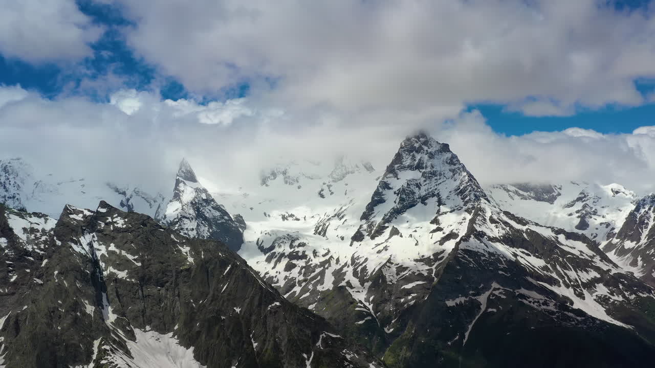 vuelo aéreo a través de nubes montañosas sobre hermosos picos nevados de montañas y glaciares.
