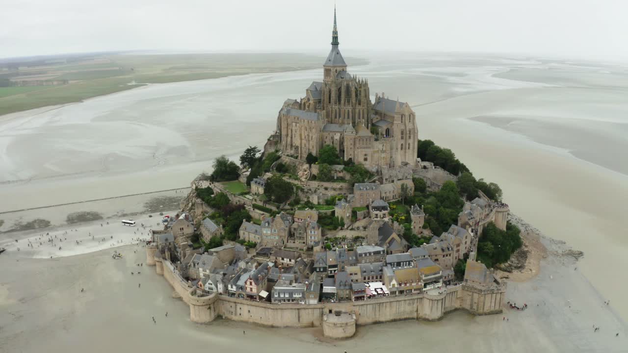 cámara de dron de mont saint michel tomando cinemáticas filmadas desde el ángulo superior, muchos jardines al lado del edificio