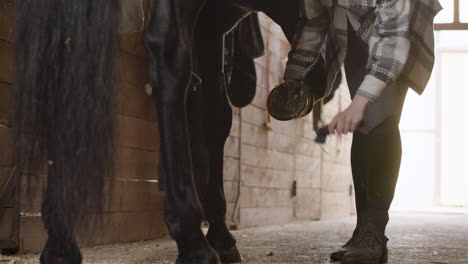 female jockey cleaning horse's hoof and horseshoe