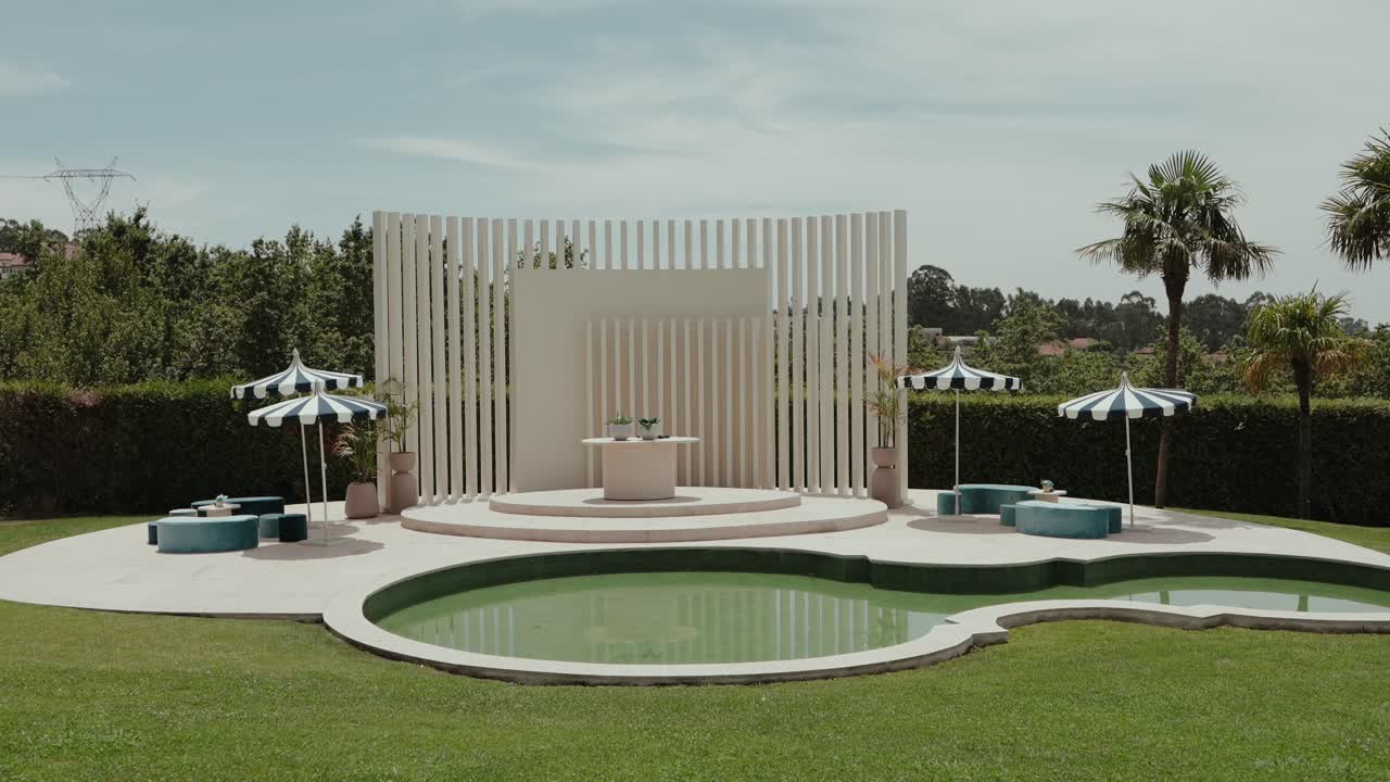 Allestimento di matrimonio contemporaneo con palco, piscina e area salotto in giardino.