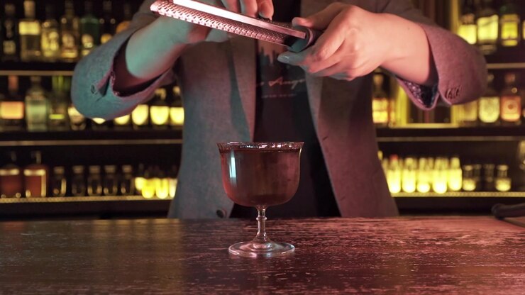 Barman elegante e alla moda che prepara un cocktail in un bar.