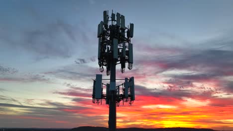 cell tower silhouetted against a vibrant sunset sky