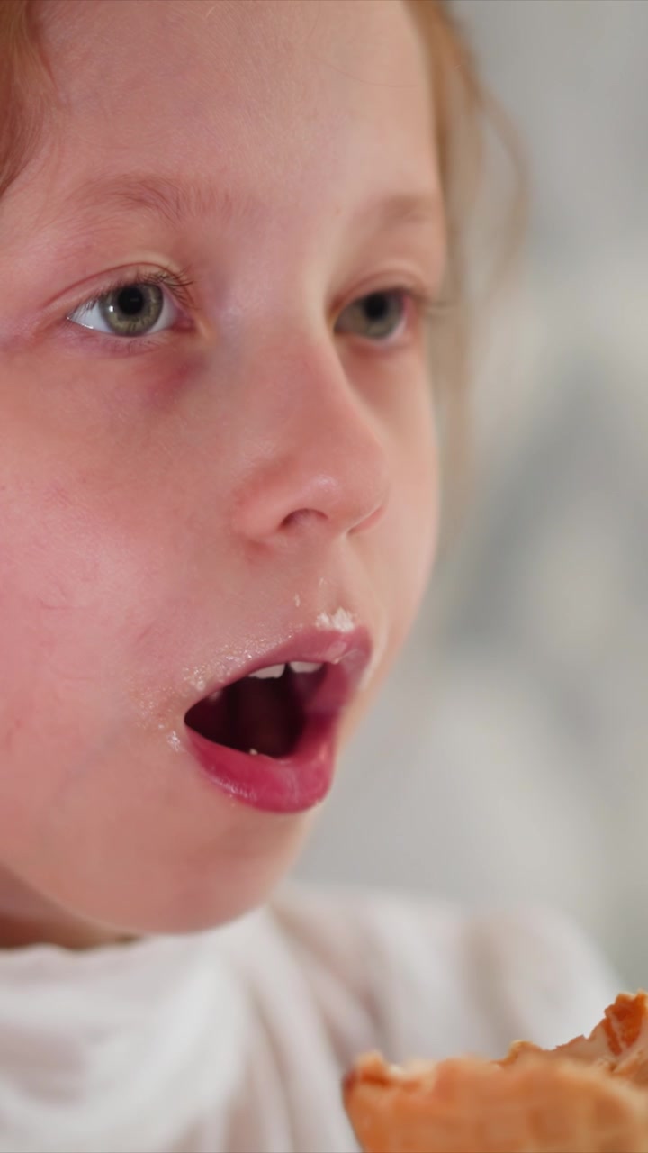 Close up of young girl enjoying ice cream cone repeatedly bringing it to her mouth and taking small bites. waffle texture is clearly visible as girl eats with soft lighting highlighting