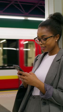 woman waiting for train and using phone at subway station