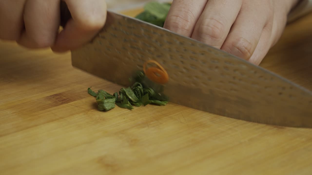el chef corta hojas de menta con un cuchillo de cocina en una tabla cortada de madera