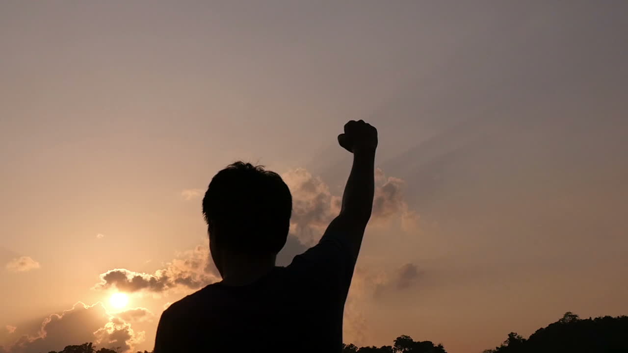 Silhouette of Person Raising Fist at Sunrise/Sunset