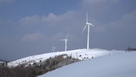 wind power plants are seen in the snow-covered mountain, south korea