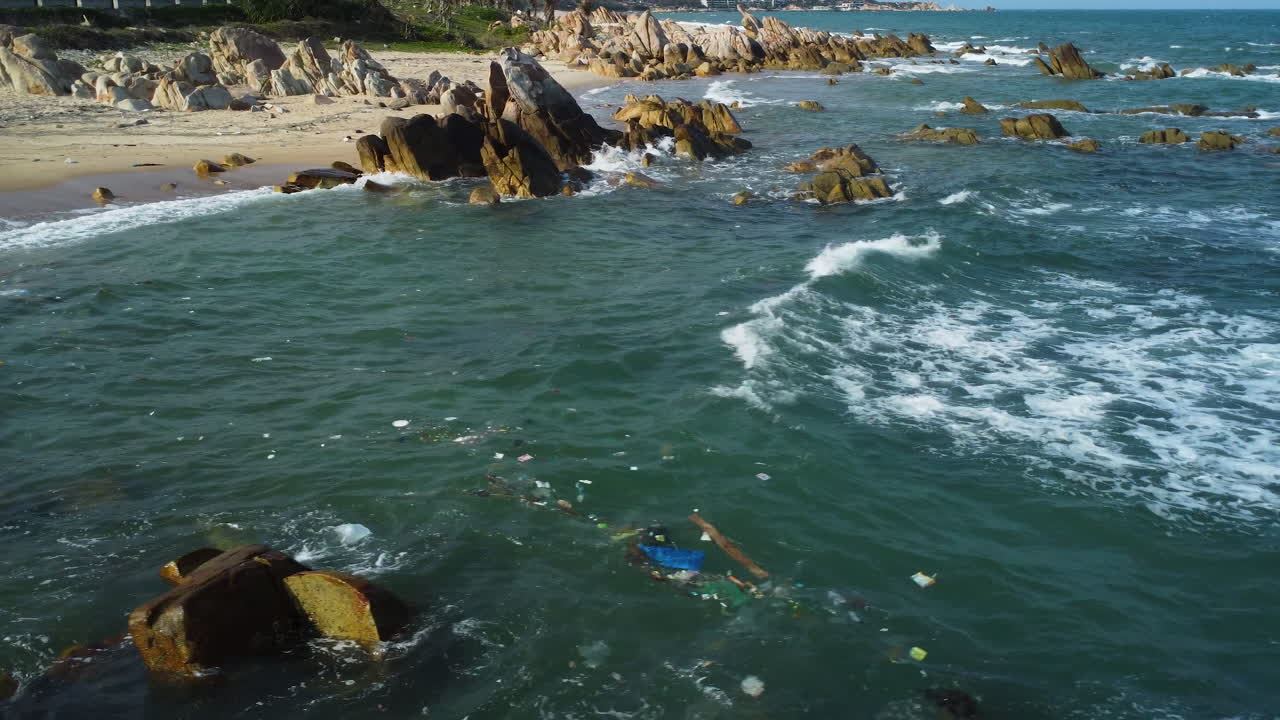 basura tirada flotando en el océano frente a la orilla de una playa de basura en vietnam