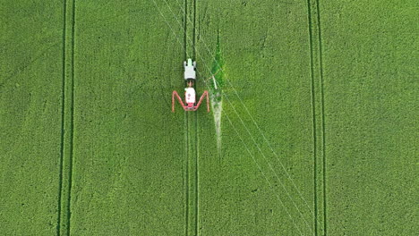 aerial top-down view of a crop duster spraying a green field