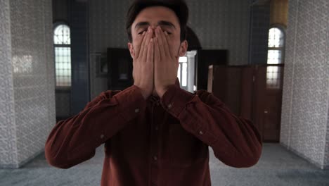 a young bearded man standing inside mosque praying to god, muslims who go to historical and holy places pray