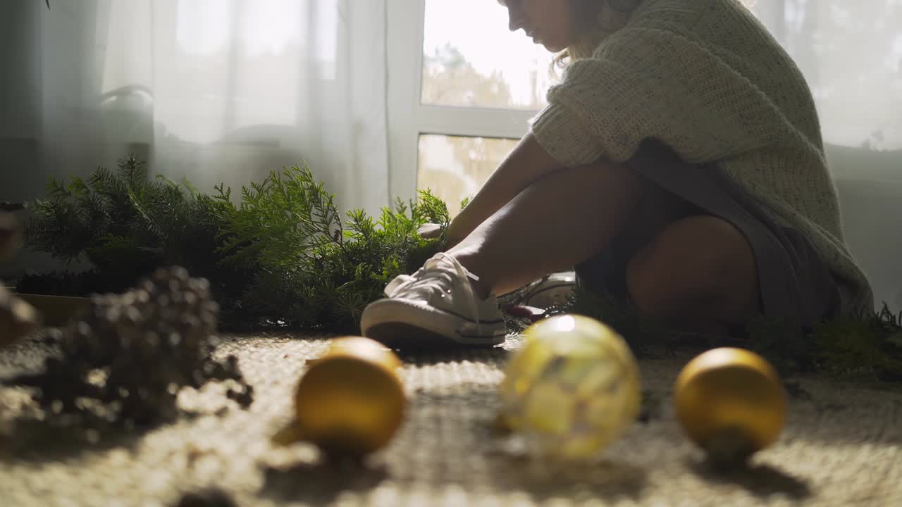 Donna decora ghirlanda festiva con palla giocattolo per Natale
