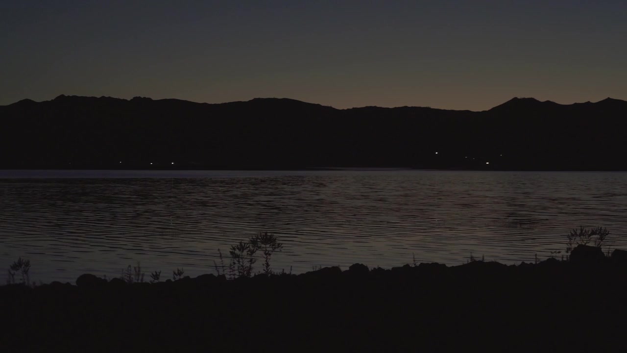 Luci lontane riflesse su un lago calmo di notte