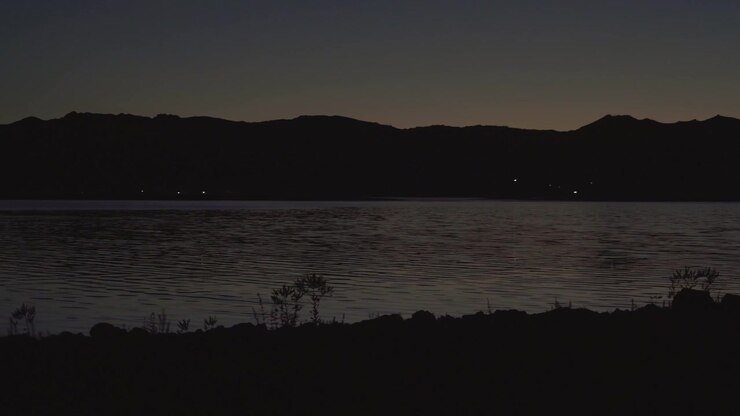 Luci lontane riflesse su un lago calmo di notte