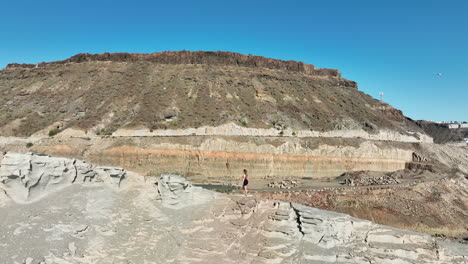 Toma-Aérea-Con-Seguimiento-De-Una-Joven-Escalando-Una-Montaña-En-Un-Acantilado