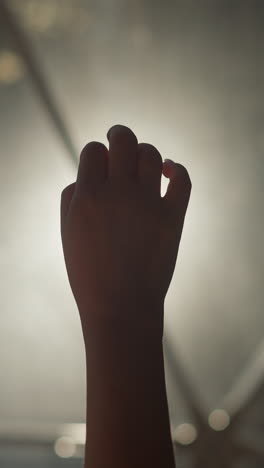 woman hand plays with finger in dark room closeup. lady arm silhouette does elegant gestures against glowing lamp in dark space. body language signs