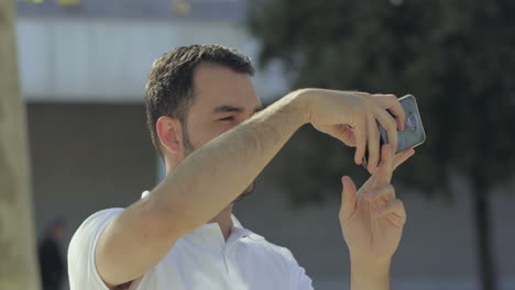 Un-Joven-Apuesto-Y-Sonriente-Tomando-Fotografías-Con-Un-Teléfono-Inteligente.