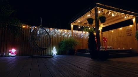 outdoor footage of a minimalistic garden at night with warm lighting, fairy lights and christmas decorations