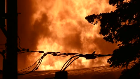 Close-up-of-giant-fire-in-building-rising-up-with-dark-smoke-at-night