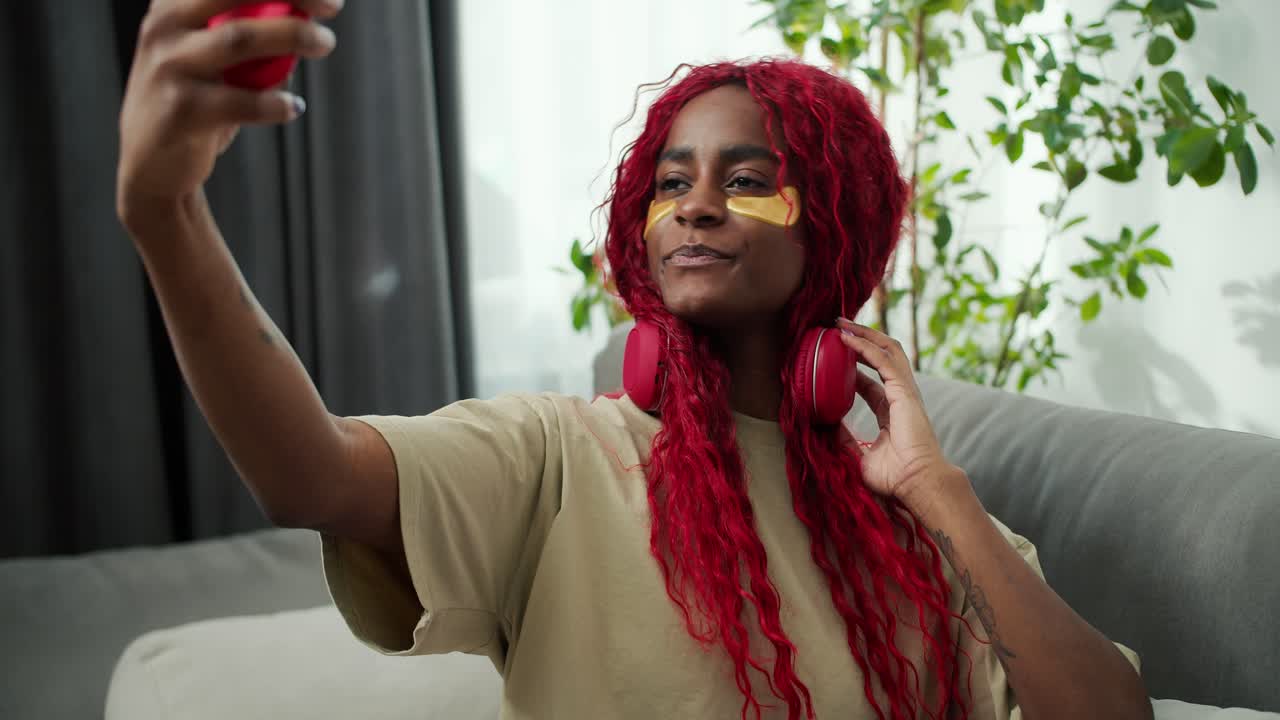 Young beautiful african woman with eye patches making selfie photo using mobile