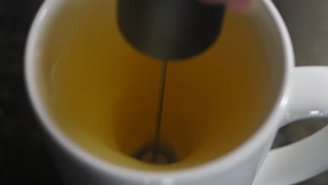 close up shot of motion of mixing orange juice in twister shape in a white cup