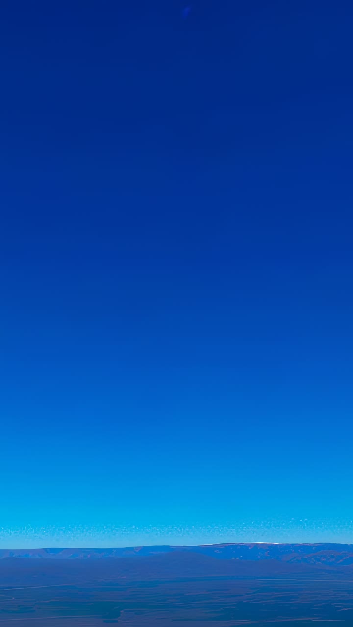 Vertical video: Panning camera revealing dry plain at high elevation, showing distant ridge and sky