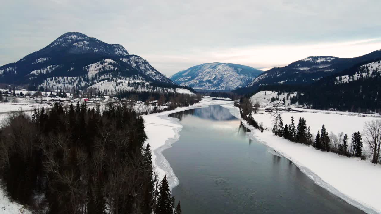 río north thompson parcialmente congelado con reflejos de montañas cubiertas de nieve capturadas en little fort, bc: una vista aérea